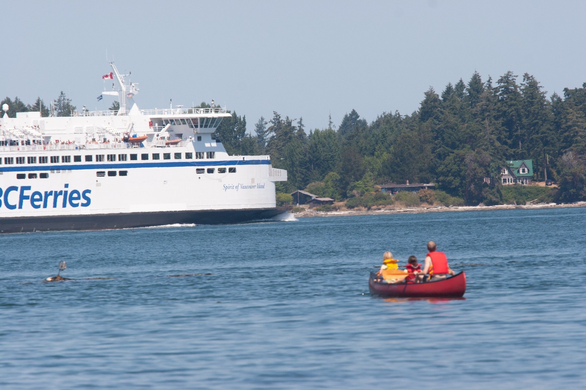 A canoe in the foreground with a BC Ferry travelling through Active Pass
